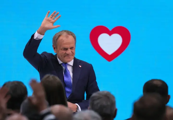 Donald Tusk macha do tłumu na tle niebieskiego ekranu z sercem. Czy to koalicja?