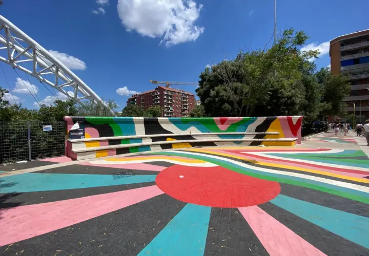 Piazza colorata vicino alla metro Garbatella a Roma, con un murale vivace e un grande sole stilizzato sul pavimento.