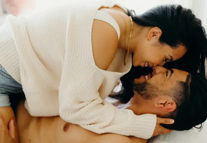 A couple embracing intimately, with the woman leaning over the man.