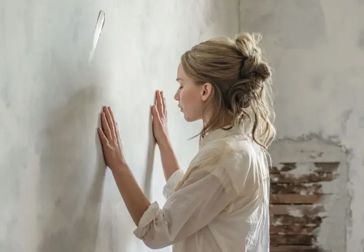 Donna con le mani sul muro, forse in attesa di una notizia o in un momento di riflessione. Una madre in attesa, la sua recensione interiore.