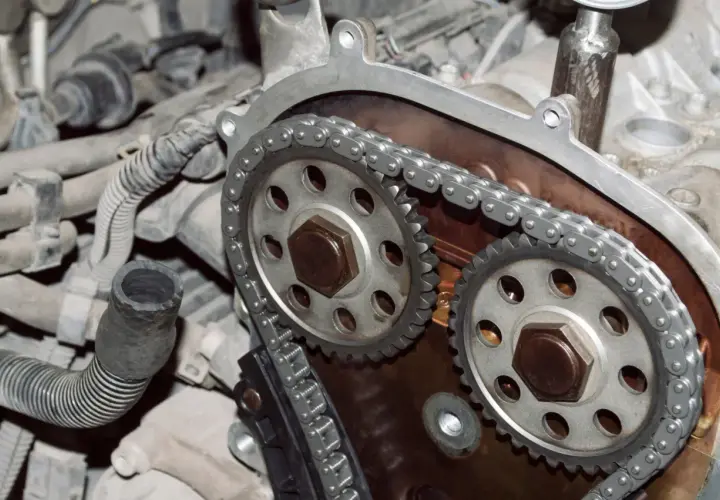 Primer plano de un motor con cadena de distribución, mostrando los engranajes y la cadena metálica.