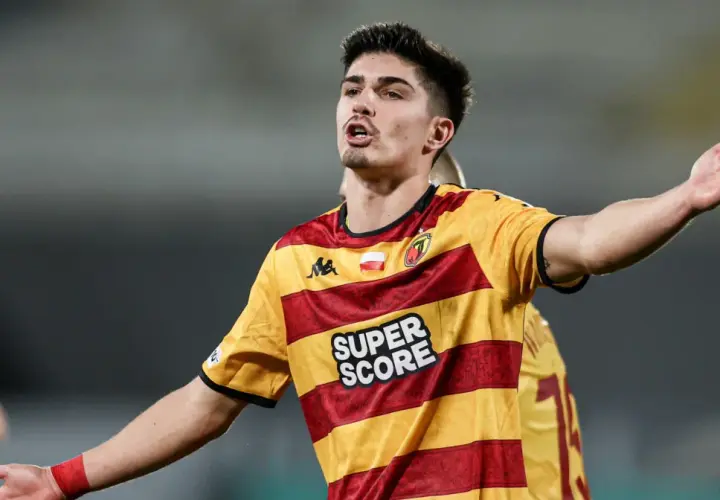 Piłkarz Korony Kielce w żółto-czerwonej koszulce z napisem "SUPER SCORE" gestykuluje podczas meczu z Jagiellonią Białystok.