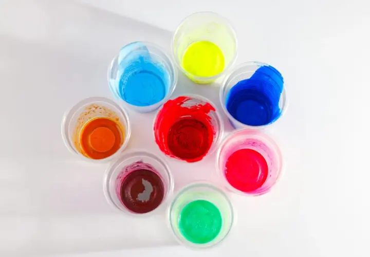 Kolorowe farby w kubeczkach, idealne jako jaka farba do plastiku na zewnątrz. Odcienie czerwieni, niebieskiego, zieleni, żółci, pomarańczu i różu.
