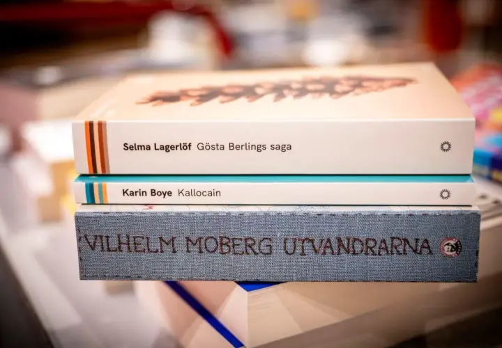 En stapel böcker med Selma Lagerlöf, Karin Boye och Vilhelm Moberg. Ur ett annat person perspektiv ser man titlarna tydligt.