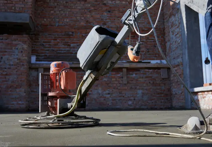 Robot do zacierania betonu pracuje na budowie, wygładzając świeżą posadzkę.