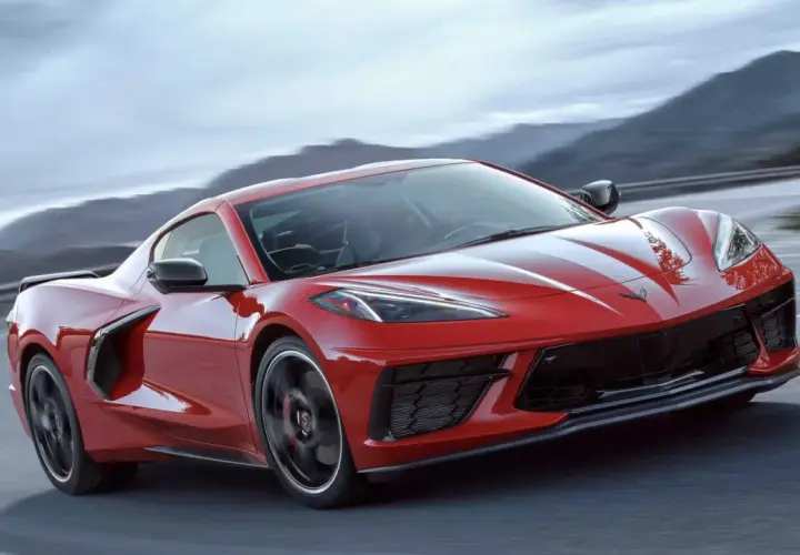 Czerwony Chevrolet Corvette C8 z białymi pasami pędzi po krętej drodze wśród gór.