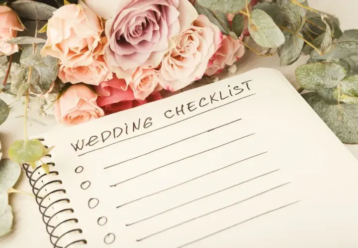 Bukiet róż i eukaliptusa obok notatnika z napisem "Wedding Checklist". Idealny punkt, od czego zacząć planowanie wesela.