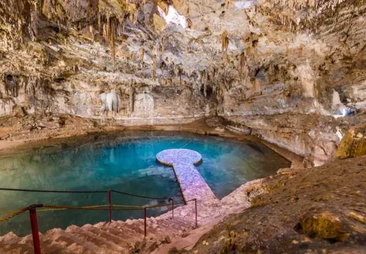 Ein atemberaubender Cenote in Mexiko mit kristallklarem, türkisfarbenem Wasser, Stalaktiten und einer steinernen Plattform.