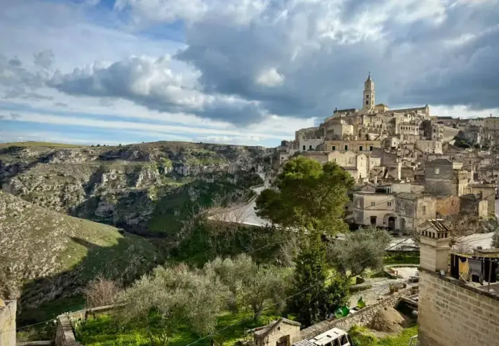 Ancient cave dwellings and a bell tower rise from a hillside in Matera, Italy. Explore this historic city for unique things to do.