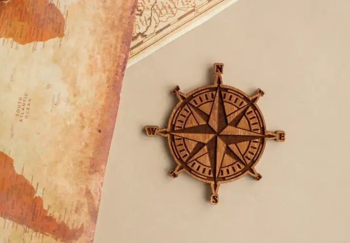 Rosa de los vientos de madera, símbolo de guía y el rosa de los vientos significado espiritual. Un mapa antiguo y una brújula de madera.