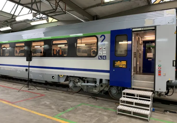 Wagon 175a w hali serwisowej, z otwartymi drzwiami i schodkami. Widać wnętrze z siedzeniami i numer wagonu "2".