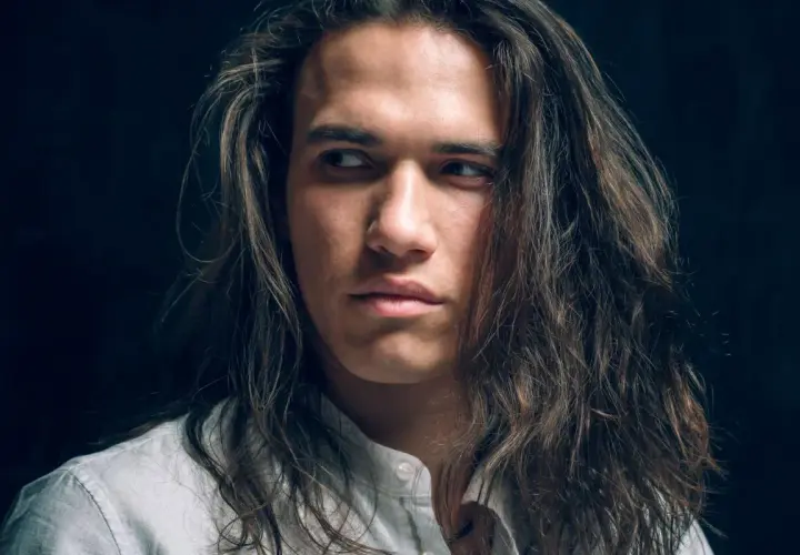Joven con cabello largo y castaño, con un estilo que resalta el cuidado del cabello hombre.