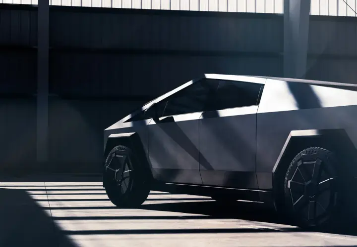 Futurystyczny Cybertruck Tesla w surowym wnętrzu, oświetlony promieniami słońca.