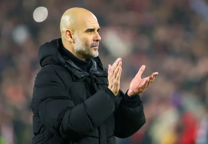 Pep Guardiola, uznawany za najlepszego trenera na świecie, klaszcze na tle trybun.
