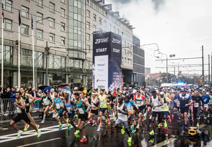 Uczestnicy biegu na 100 km startują w Poznaniu. Tłum biegaczy rusza spod wielkiego banera z napisem "START".