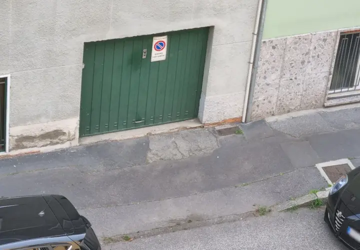 Porta garage verde con cartello "passo carrabile". Spazio di manovra libero.