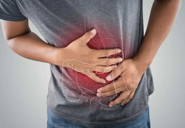 Uomo con mani sull'addome, evidenziato da un'area rossa e un contorno stilizzato dell'intestino. Potrebbe cercare rimedi per la cattiva digestione.