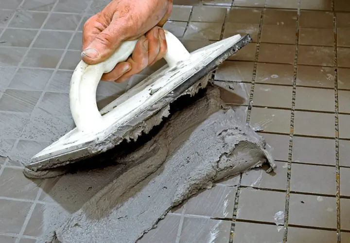 Hand spreading cement with a trowel to foga om kakel.