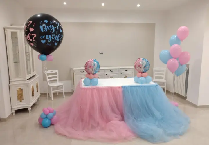 Un allestimento per un baby shower con palloncini rosa e azzurri, che simboleggiano il significato di "boy or girl?".