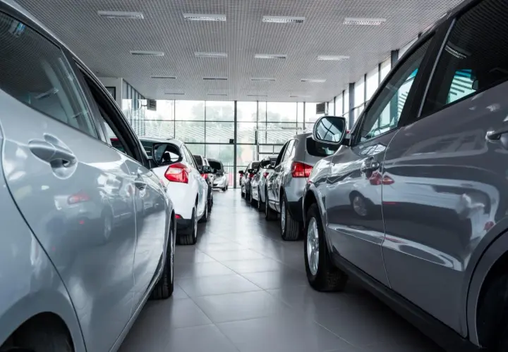 Auto km 0: cosa controllare. Diverse auto nuove in fila in un concessionario, pronte per essere visionate.