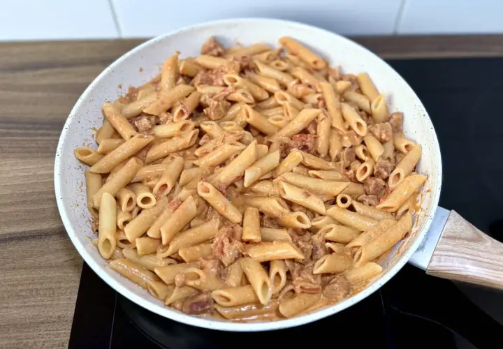 Penne z kremowym sosem i kawałkami pikantnego chorizo, przygotowane na patelni.