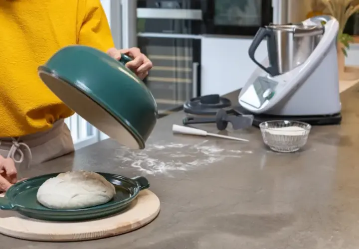 Préparation de la pâte à pizza avec un robot culinaire. Une boule de pâte repose sur un plat vert, prête à être cuite.