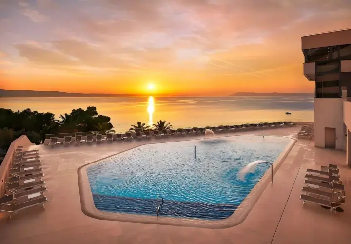 Zachód słońca nad basenem w Medora Auri Family Beach Resort. Woda w basenie lśni, a leżaki czekają na gości.