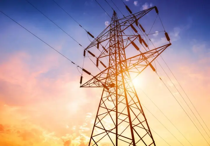 Słupy energetyczne na tle zachodzącego słońca. Zastanawiasz się, ile wynosi odszkodowanie za słupy energetyczne na działce?
