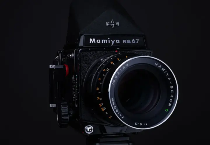 Czarny aparat Mamiya RB67 z obiektywem Mamiya-Sekor C f=180mm. Idealny do zdjęć, które wymagają precyzji i jakości, jaka klisza do aparatu jest w stanie zapewnić.