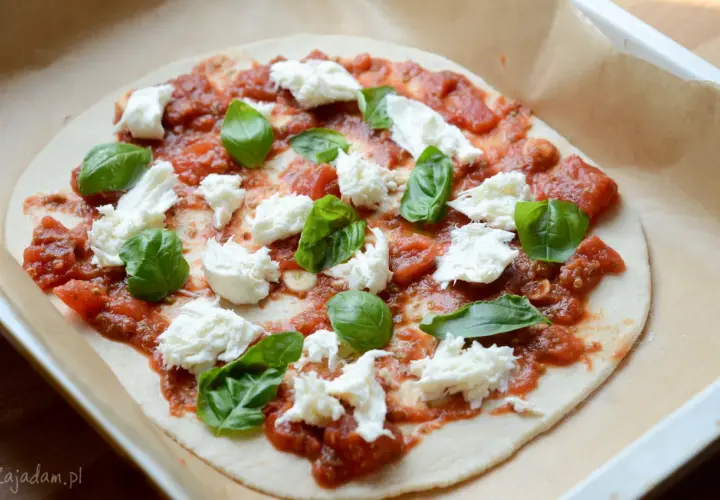 Pizza mozzarella z pomidorami i bazylią, gotowa do pieczenia.