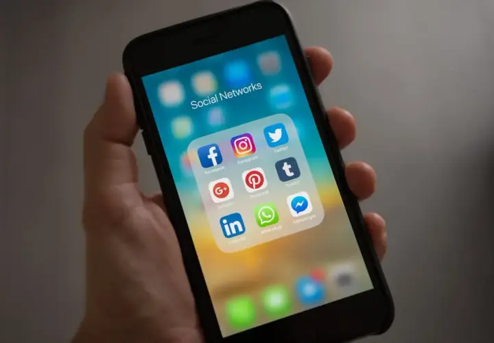 Dłoń trzyma smartfon z ikonami mediów społecznościowych. Idealne narzędzia dla każdego social media managera do zarządzania profilami.