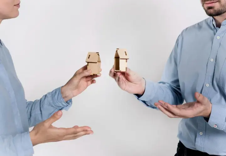 Rozdzielność majątkowa a wspólny dom: dwoje ludzi trzyma miniaturowe domki, symbolizujące podział majątku.
