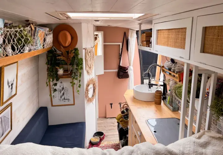 Ambiance chaleureuse et bohème pour ce deco interieur van. Un canapé bleu, des plantes grimpantes, un chapeau tendance et une cuisine fonctionnelle.