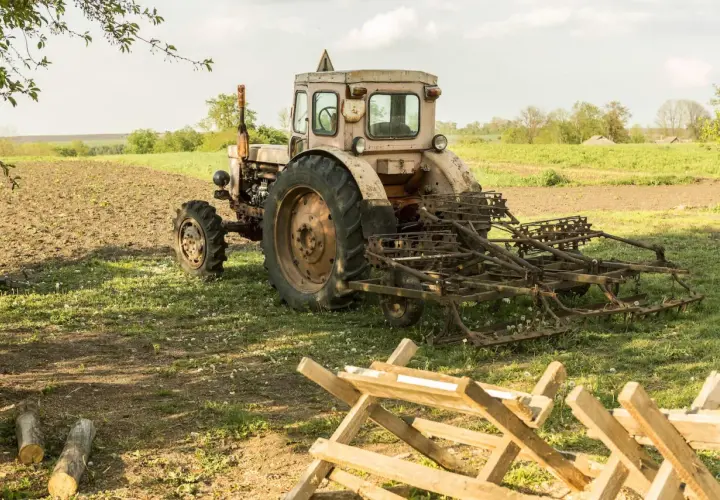 Stary traktor z pługiem na polu. Warto wiedzieć, jak przerejestrować ciągnik po śmierci właściciela, by móc dalej pracować.