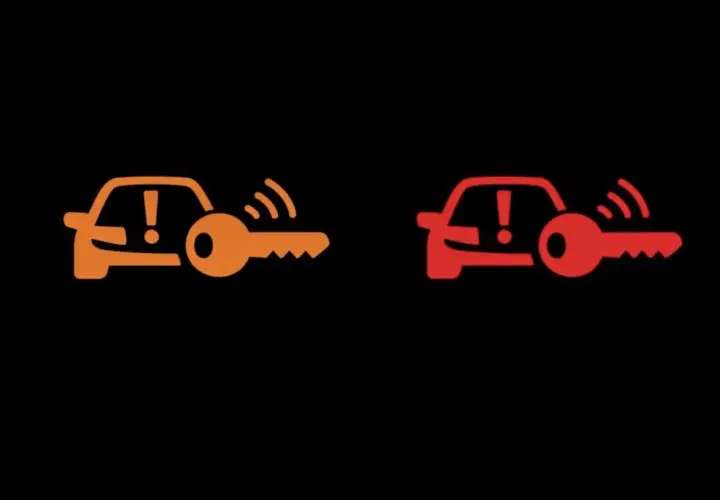 Pomarańczowa i czerwona kontrolka auto z kluczem. Sygnalizuje problem z immobilizerem lub kluczykiem.