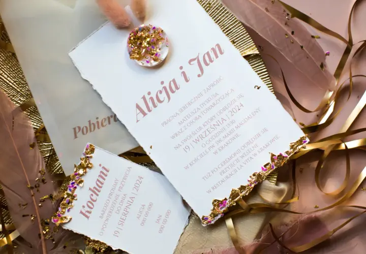 Eleganckie zaproszenia ślubne z ozdobnymi piórami i złotymi elementami.