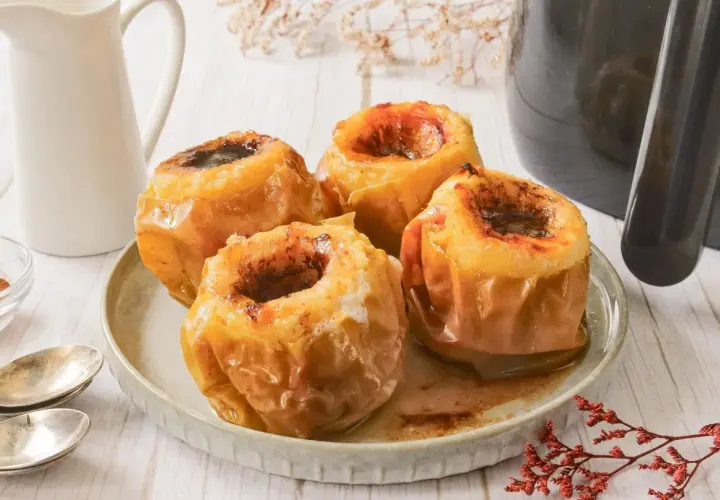 Cuatro deliciosas manzanas asadas en freidora de aire, con un relleno dulce y especiado, listas para disfrutar.