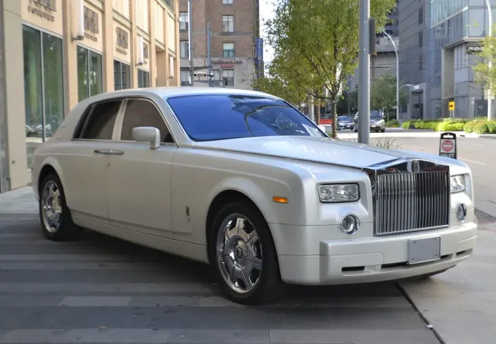 Biały Rolls-Royce, idealny na umowę transportu okazjonalnego, lśni na tle miejskiej architektury.
