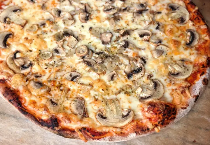 Pyszna, gorąca pizza domowa z pieczarkami i ciągnącym się serem. Idealna na wieczór filmowy.