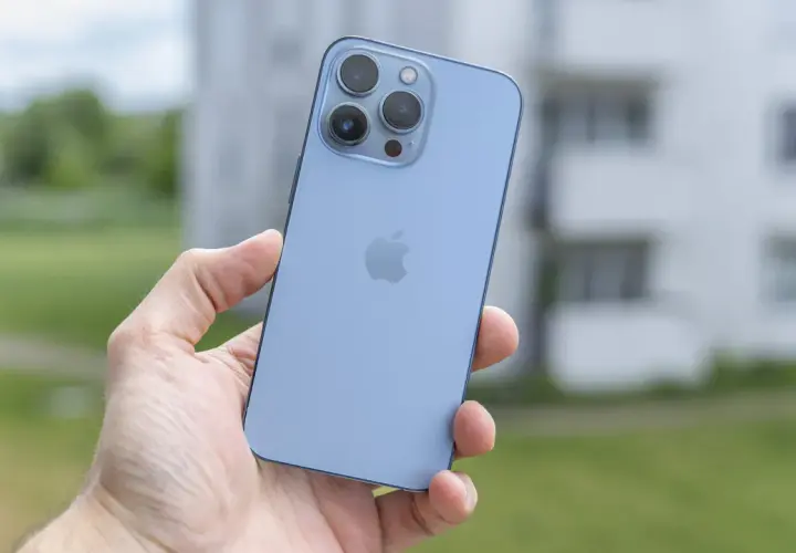 Niebieski iPhone 13 Pro z potrójnym aparatem w dłoni, gotowy do uchwycenia pięknych chwil.