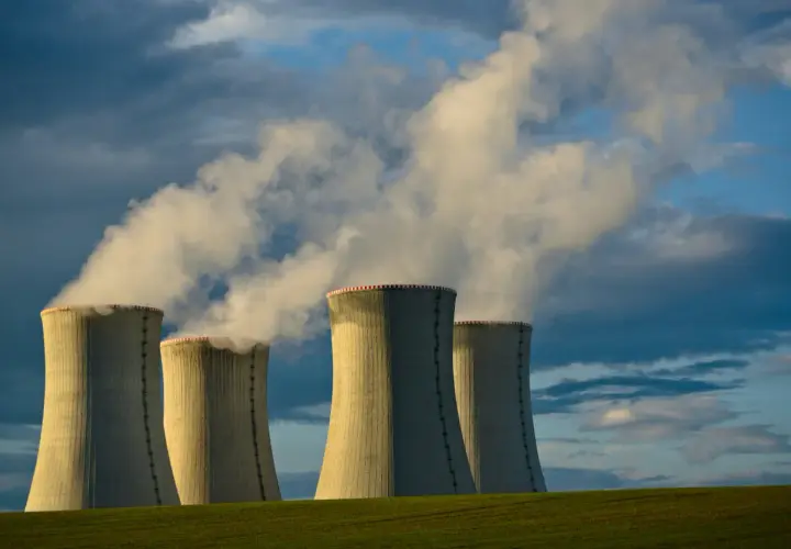 Chłodnie kominowe elektrowni jądrowej na tle burzowego nieba. Czy energia jądrowa jest ekologiczna? Dym unoszący się z kominów budzi pytania.