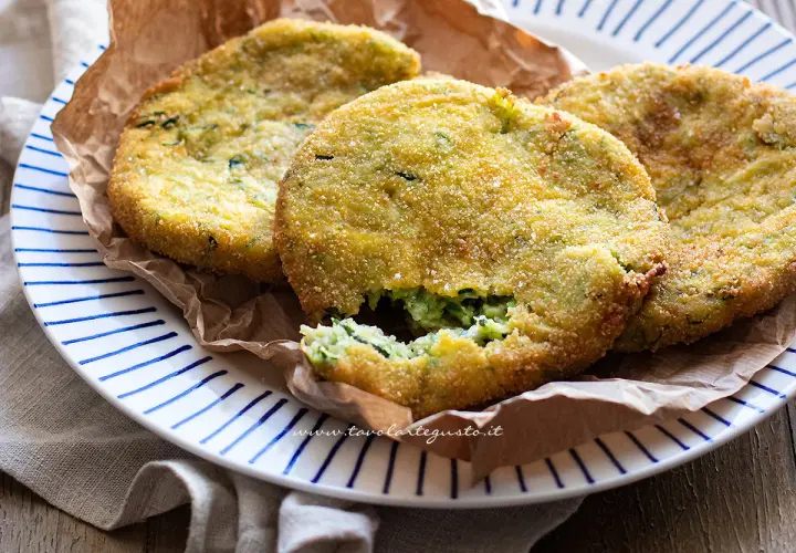 Crocchette di zucchine al forno, dorate e croccanti, servite su un piatto a righe blu.