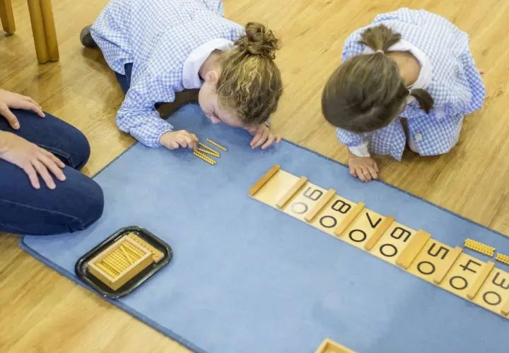Niñas aprendiendo con el método Montessori en colegios, usando cuentas para sumar.