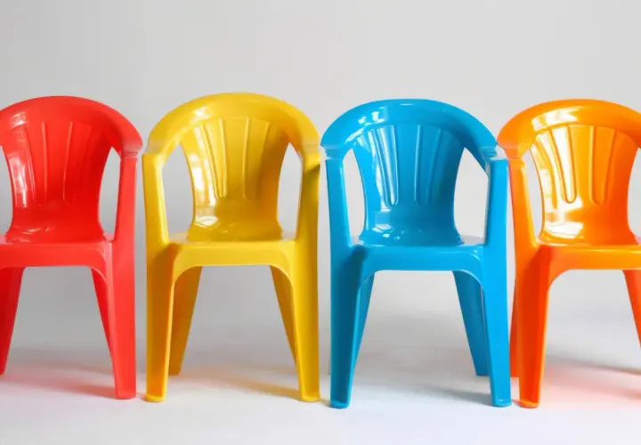 Cztery kolorowe plastikowe krzesełka: czerwone, żółte, niebieskie i pomarańczowe. Idealne do ogrodu, zastanawiasz się, czym pomalować plastik?