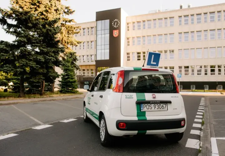 Biały Fiat Panda z zielonym pasem i literą "L" na dachu, gotowy do nauki jazdy. To auto jest kluczowe, gdy zastanawiasz się, co jest potrzebne do odbioru prawa jazdy.