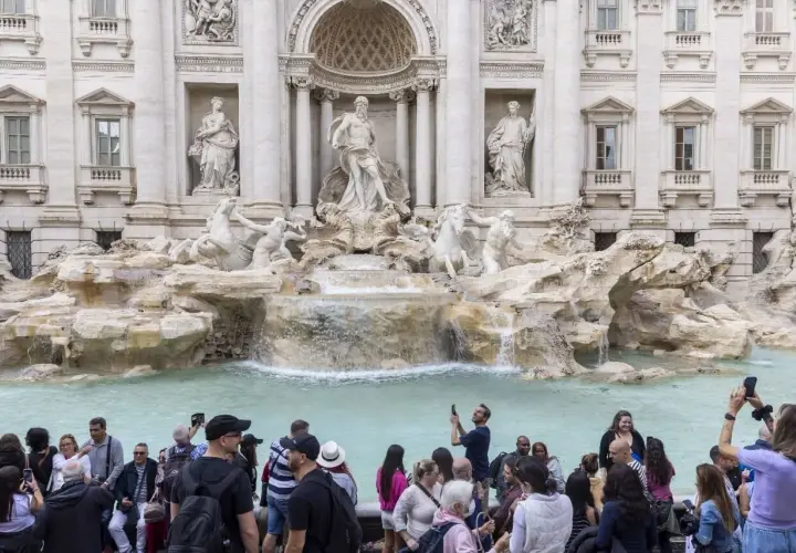 La fontaine de Trevi, avec ses statues majestueuses et ses chevaux marins, attire une foule de visiteurs capturant ce moment magique avec leurs téléphones.