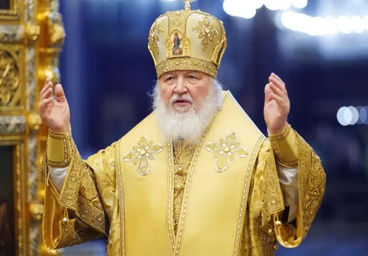 Patriarch Kyrill in golden vestments and crown, raising hands in blessing.