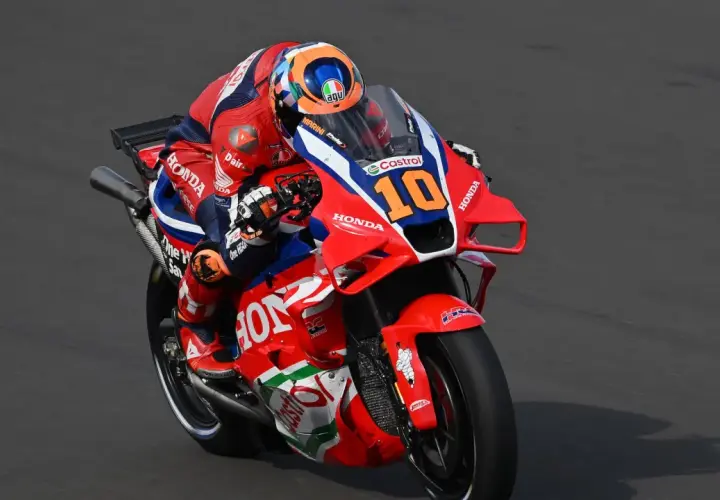 Luca Marini en su moto Honda número 10, con su traje rojo y azul, compite en la pista.