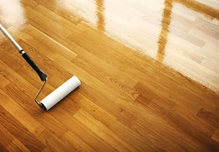 Rodillo aplicando barniz para limpiar parquet y darle un acabado brillante.