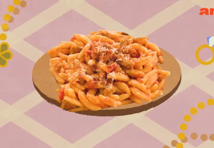 Un plat de malloreddus alla campidanese, pâtes traditionnelles sardes, servi sur une assiette dorée.